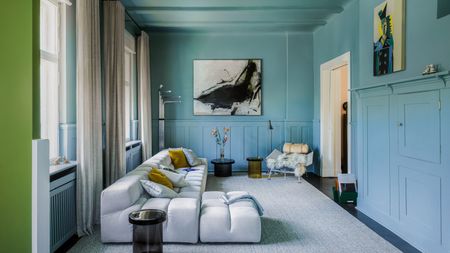 Blue living room with pale blue chaise sofa, black glass side tables and abstract artwork