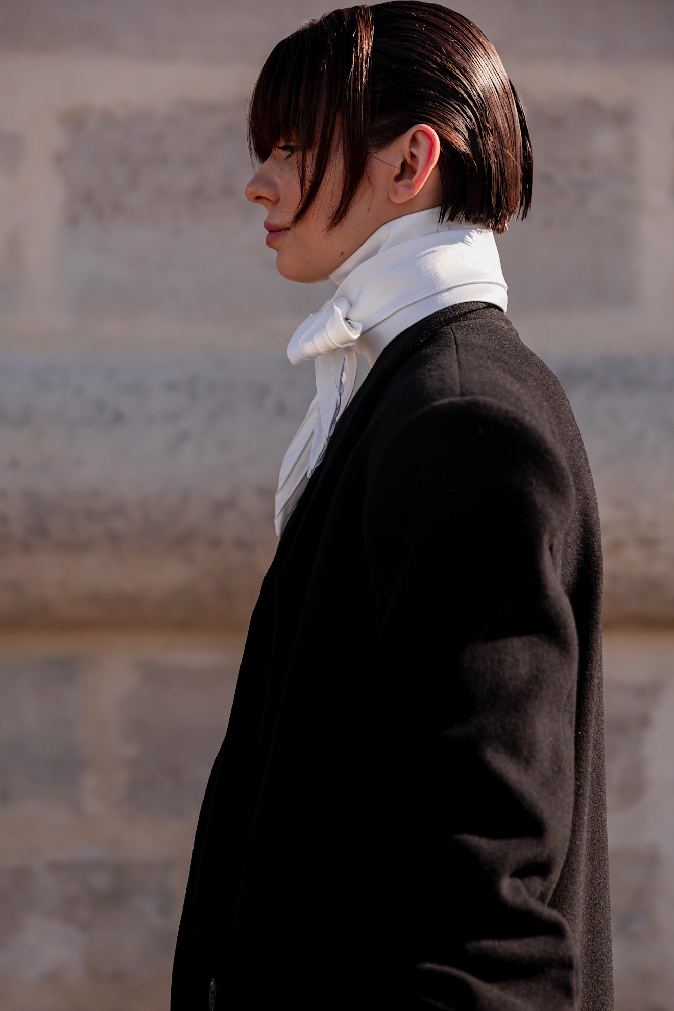 a woman in a profile with a black jacket and short brunette bob