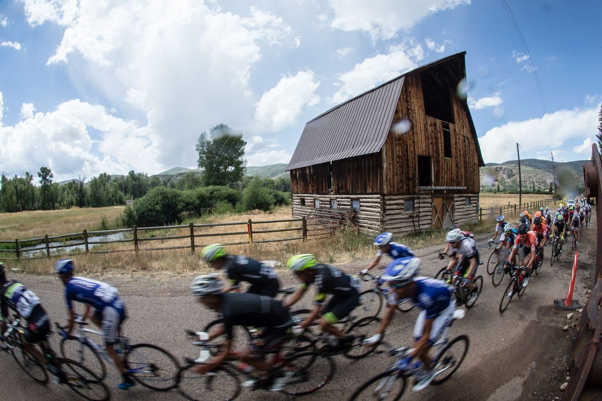 The peloton passes by an old barn as the rains start