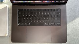 A Space Black Apple MacBook Pro 16-inch M3 sitting on a grey/blue table