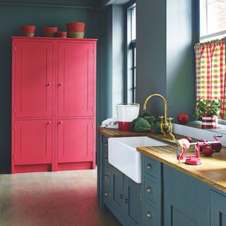 blue kitchen with pink cupboard and worktop