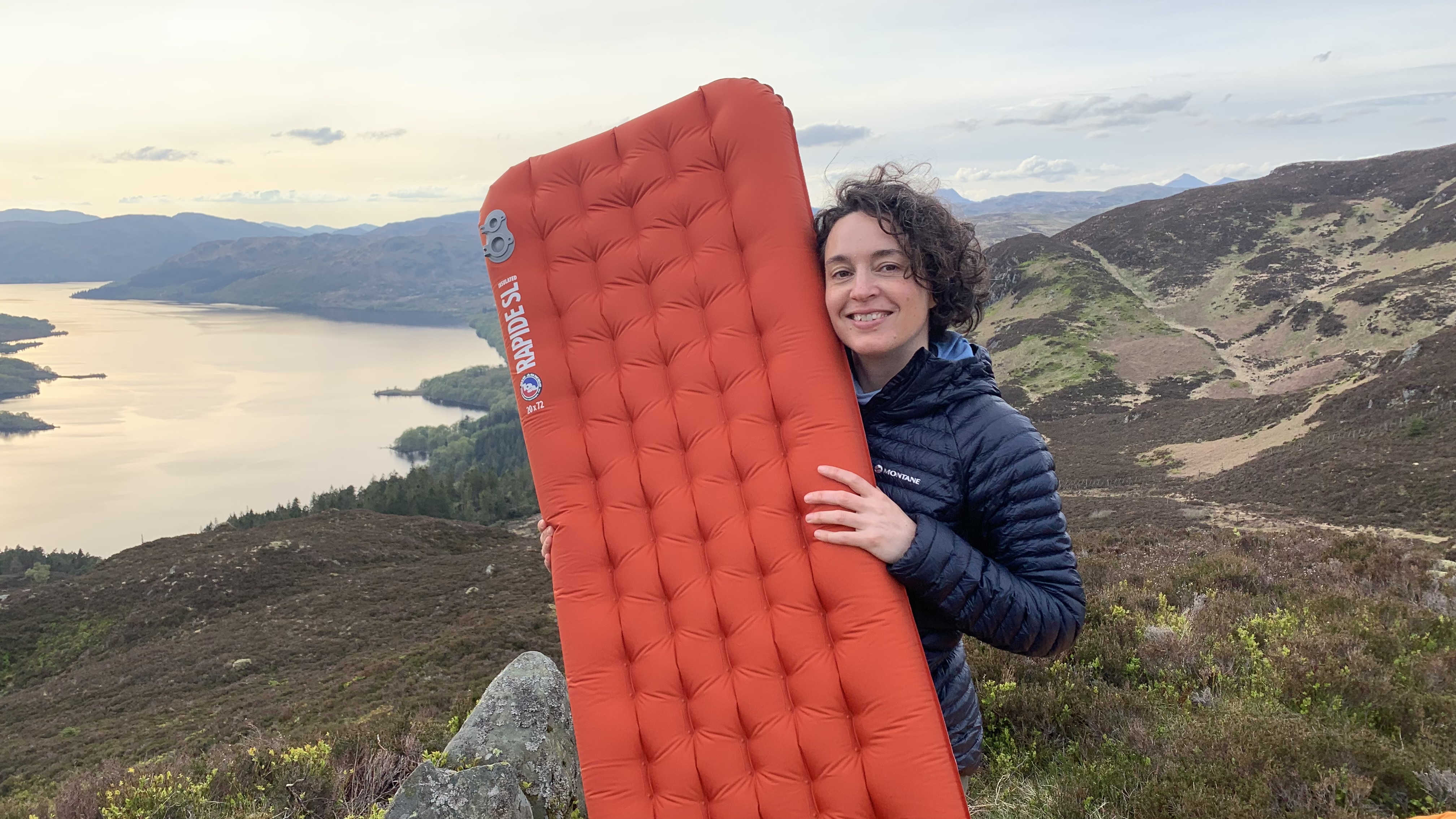 Julia Clarke holding the inflated Big Agnes Rapide SL sleeping pad on a mountain