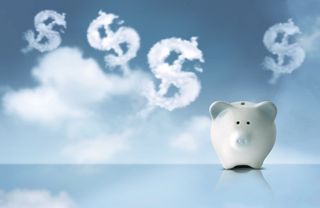 A white piggy bank sits on a reflective surface while clouds in the shape of dollar signs float in the sky behind it
