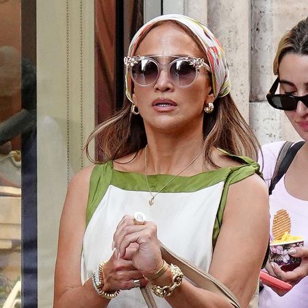 Jennifer Lopez wearing a scarf dress with a head scarf and metallic gold flip-flops in Rome, Italy
