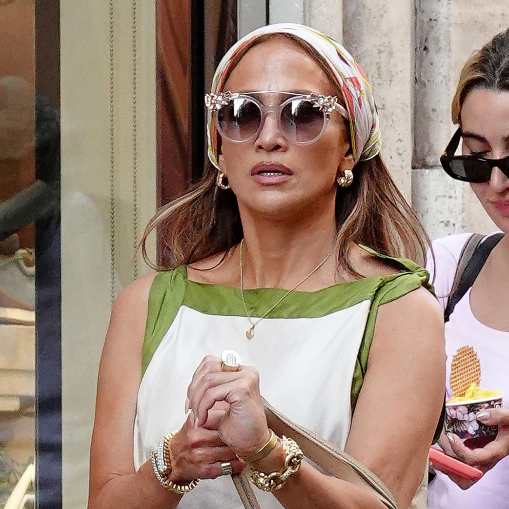 Jennifer Lopez wearing a scarf dress with a head scarf and metallic gold flip-flops in Rome, Italy