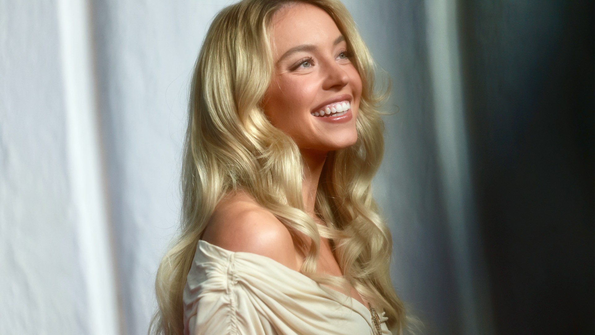 a white woman with blonde hair posing in front of a white backdrop