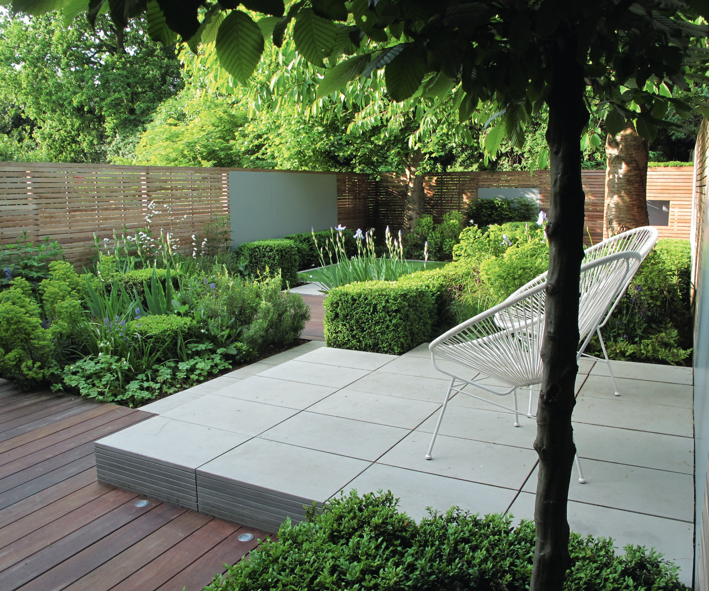 small raised paved patio area leading to planted areas and dark wooden decking