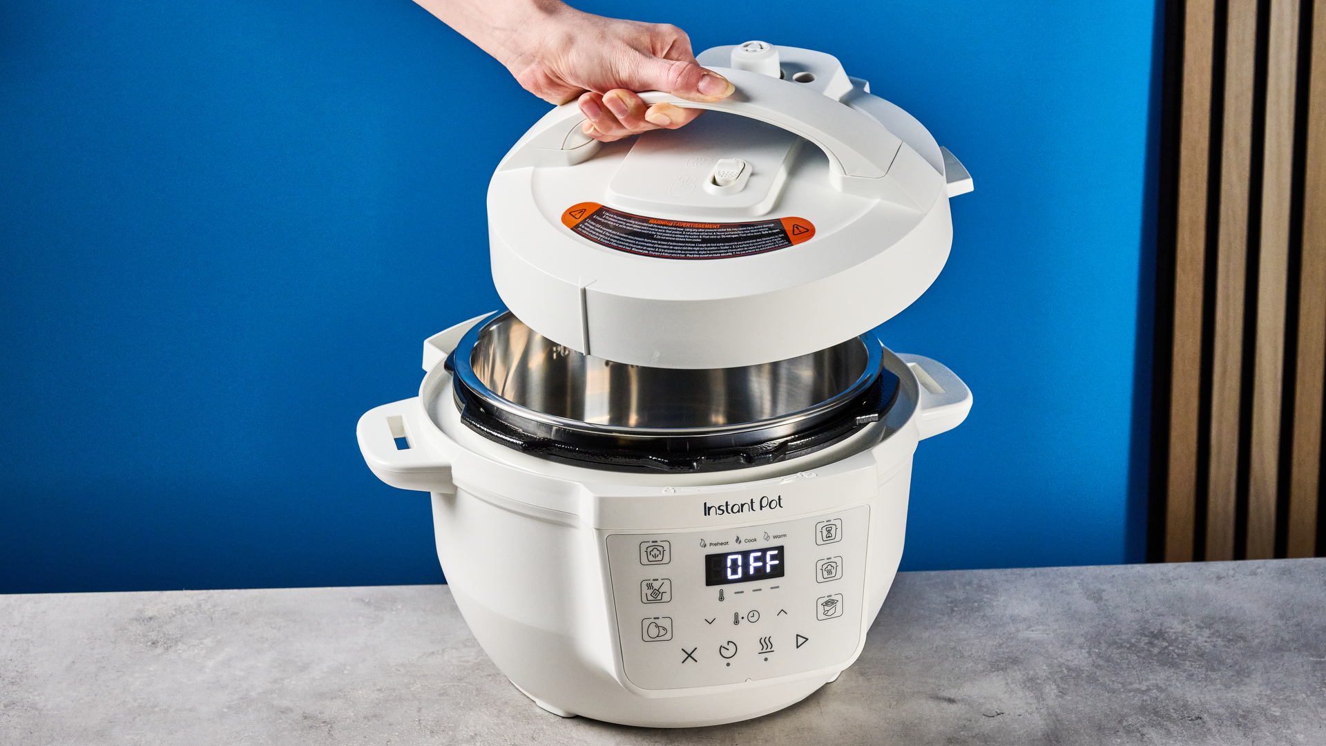 the instant pot rio mini / instant pot mini in white photographed against the blue tom's guide background showing its inner pot, accessories, and cooking programs