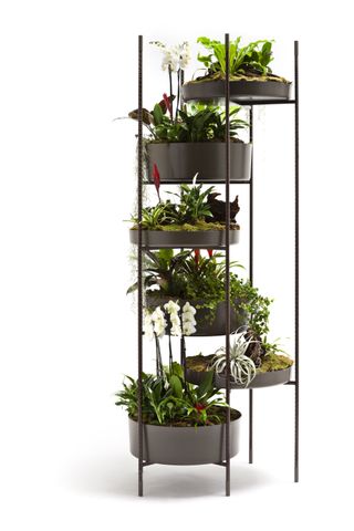 A black powder coated aluminium planter shaped like a tower with several trays for plants. Shown with green foliage throughout