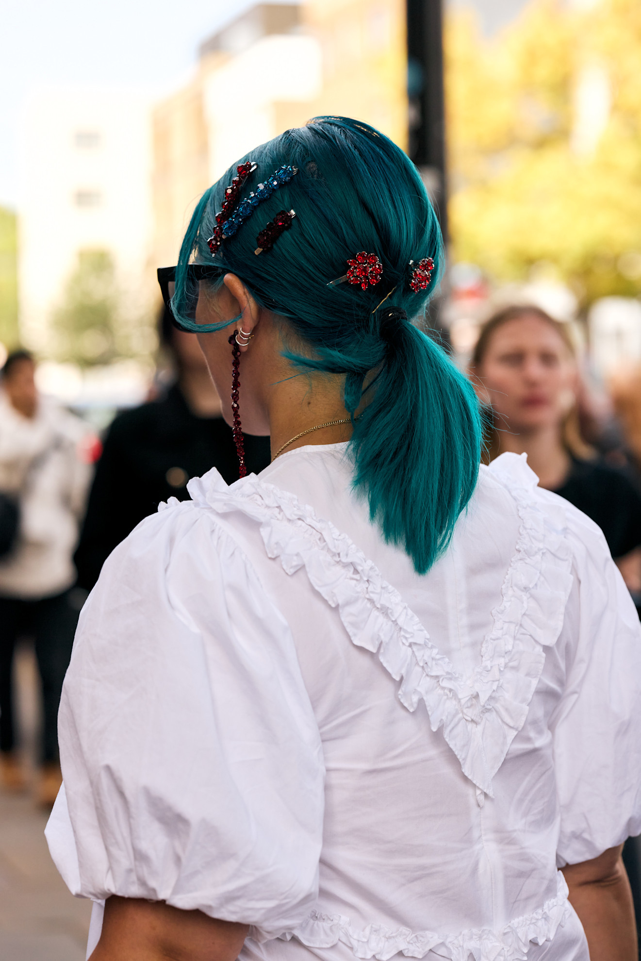 a woman with blue hair and pins from the back wearing a white top