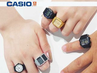 Hands wearing mini Casio rings on their fingers