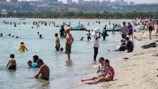 People sit along a beach in the sun
