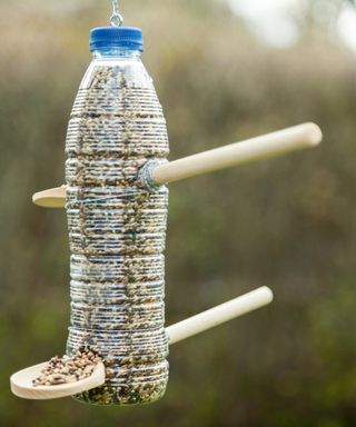 A DIY bottle bird feeder with spoons as dowels