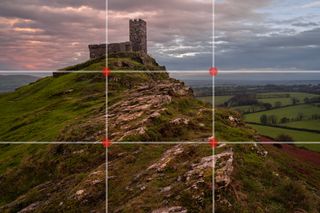 Rule of thirds grid overlaid onto image of church atop a hill with a pink sunset behind