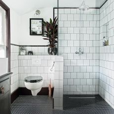 bathroom with white tiles on wall and plant