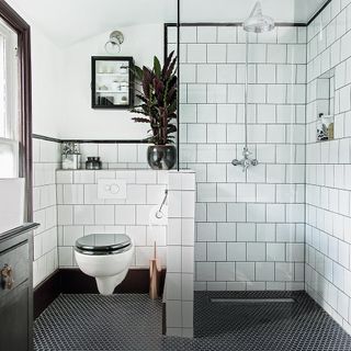bathroom with white tiles on wall and plant