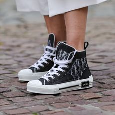 Natalia Verza @mascarada.paris wears Dior monogram printed designer sneakers, on April 16, 2021 in Paris, France