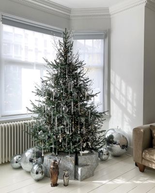 a christmas tree with silver decor and disco balls around the base