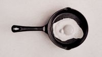 Photograph of an egg frying in a pan, edited to resemble the 1987 'this is your brain on drugs' PSA.