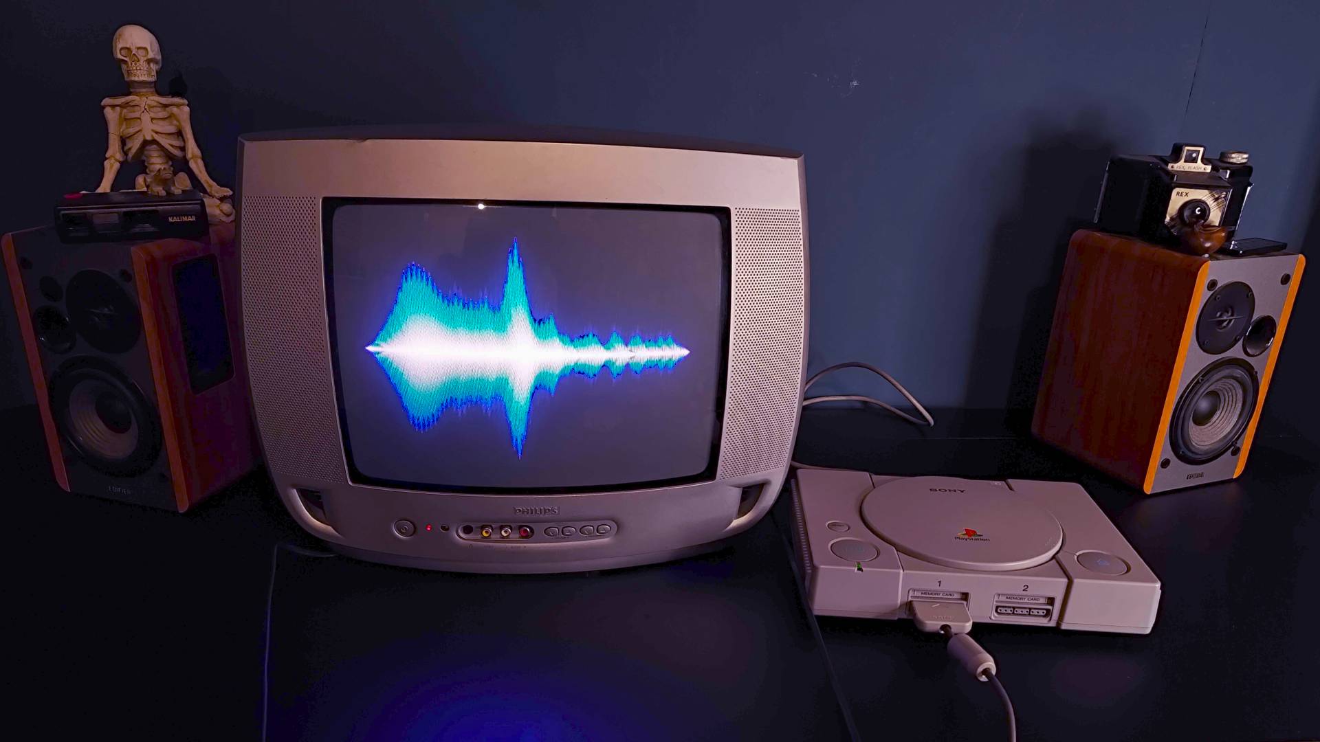 PS1 connected to Philips CRT TV and bookshelf Edifer speakers with blue visualization on screen.