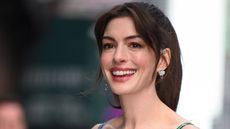 anne hathaway smiling on a gray background