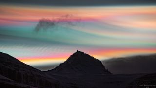 Rainbow colored clouds above a mountain peak