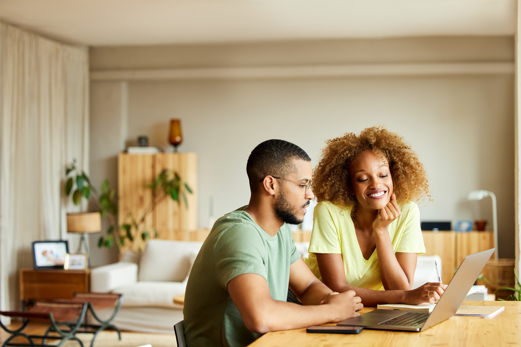 Two people working together at a table with a laptop.
