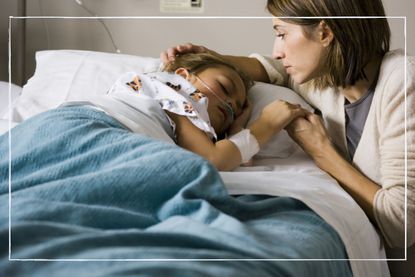 Mother comforting poorly child who is lying in a hospital bed