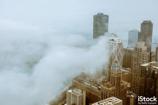 City buildings seen from a skyscraper, smothered in cloud