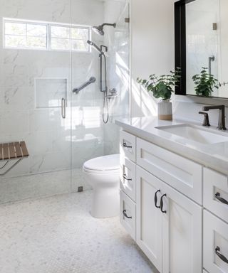 Narrow bathroom with white vanity, mosaic floor tile, toilet and glass shower