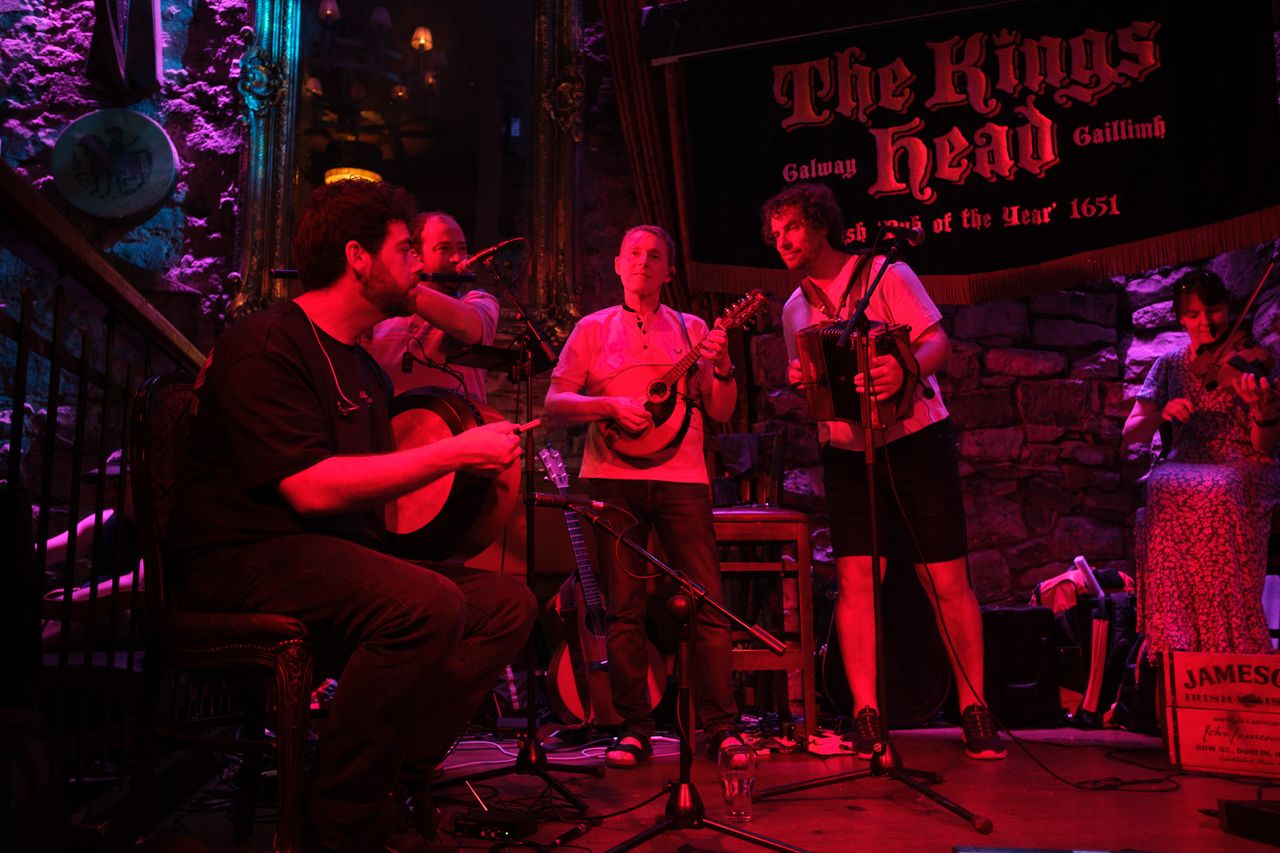 Traditional musicians play drums, guitar, banjo, accordion and fiddle onstage at The Kings Head pub in Galway.