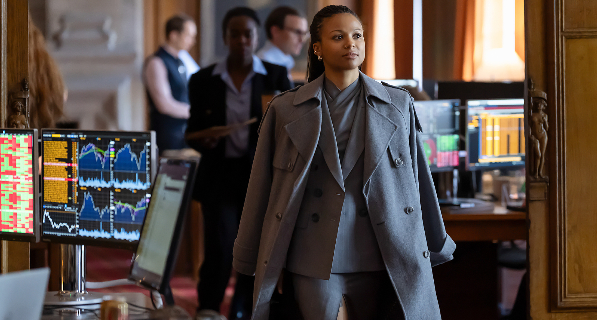 myha'la as harper wearing a grey peacoat and suit walking through an office in industry season 4