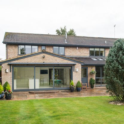 house exterior with bricked wall and glass door and garden area