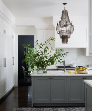 white kitchen with gray island and big chandelier