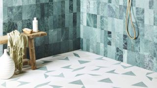 A shower with hexagonal bathroom floor tiles and blue encaustic tiles on the walls 