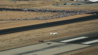 A small winged spacecraft glides to a landing on a desert strip after completing a suborbital spaceflight