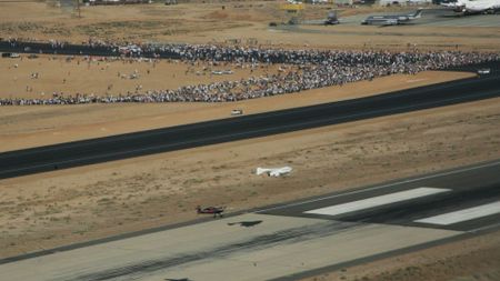 A small winged spacecraft glides to a landing on a desert strip after completing a suborbital spaceflight