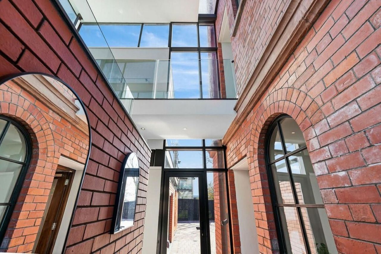 A view inside the tower showing the glass walls and windows separating the new aspects of house to divide the extension from the old red brick structure