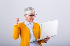 an excited older woman looking at her laptop