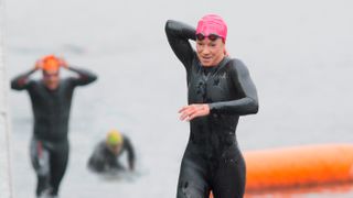 Triathlete reaching behind her to unzip her wetsuit