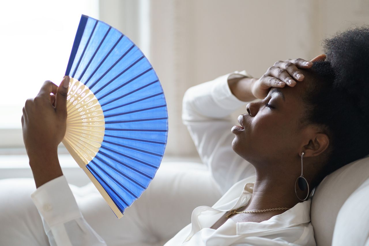 Close-Up Of Tired Woman Holding Hand Fan At Home during level 4 heatwave