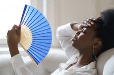 Close-Up Of Tired Woman Holding Hand Fan At Home during level 4 heatwave