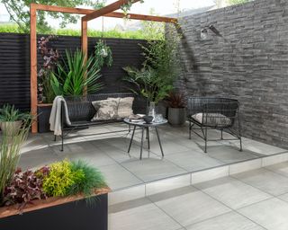 modern patio with a timber pergola and slate covered contemporary garden wall