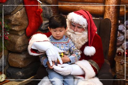 Hamleys Father Christmas chatting with child sat on his knee