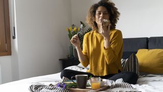 A woman eats breakfast in bed