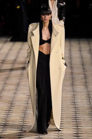 Saint Laurent model walks the spring/summer 2023 runway wearing a maxi coat