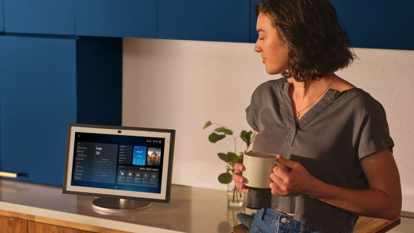 A woman leaning on a counter beside an Amazon Echo Show tablet running Alexa+