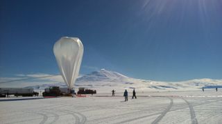 Photograph of a high-altitude balloon being inflated against a blue sky in Antarctica.