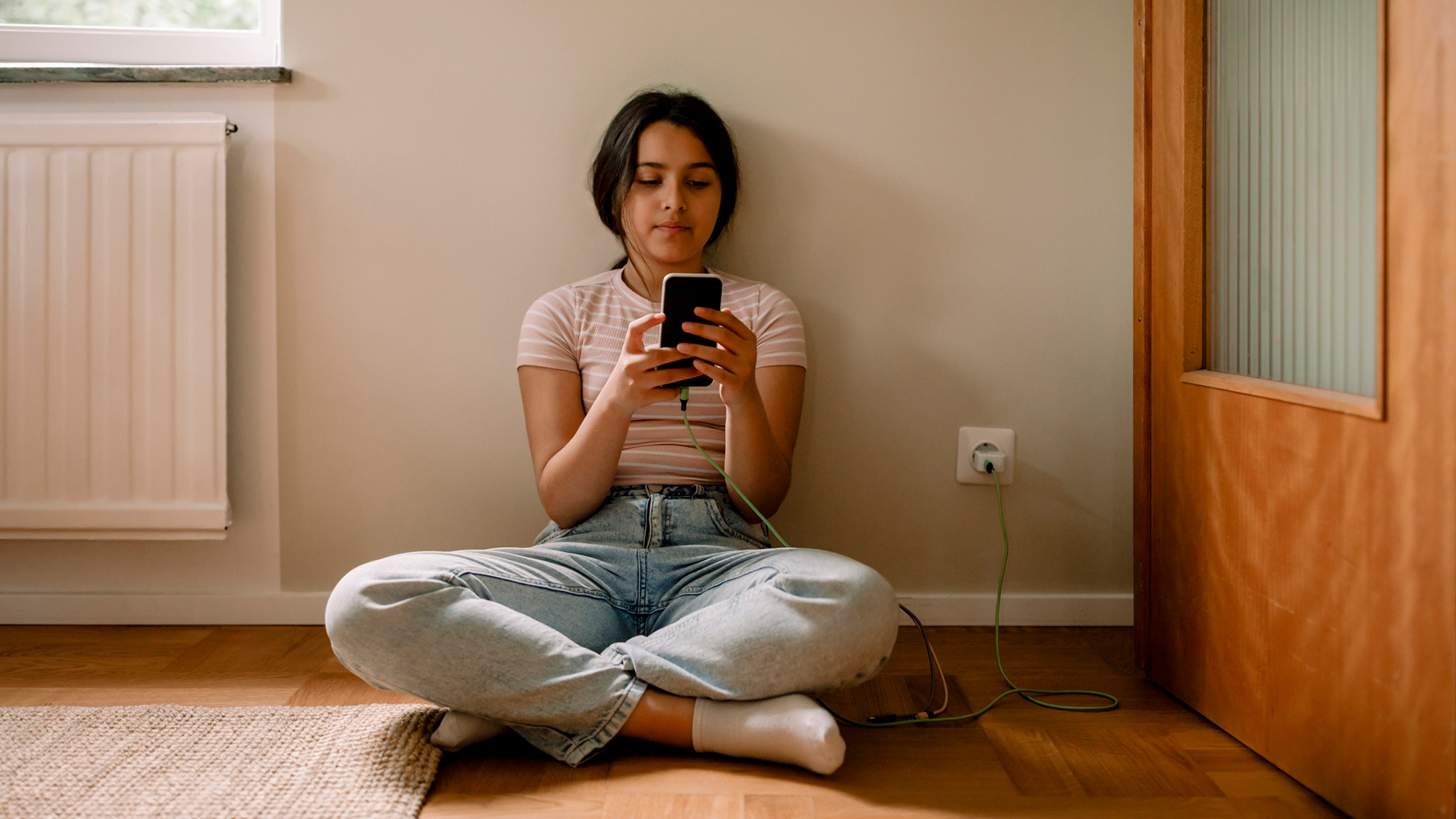 A girl sits cross-legged and holds the phone in front of her face.