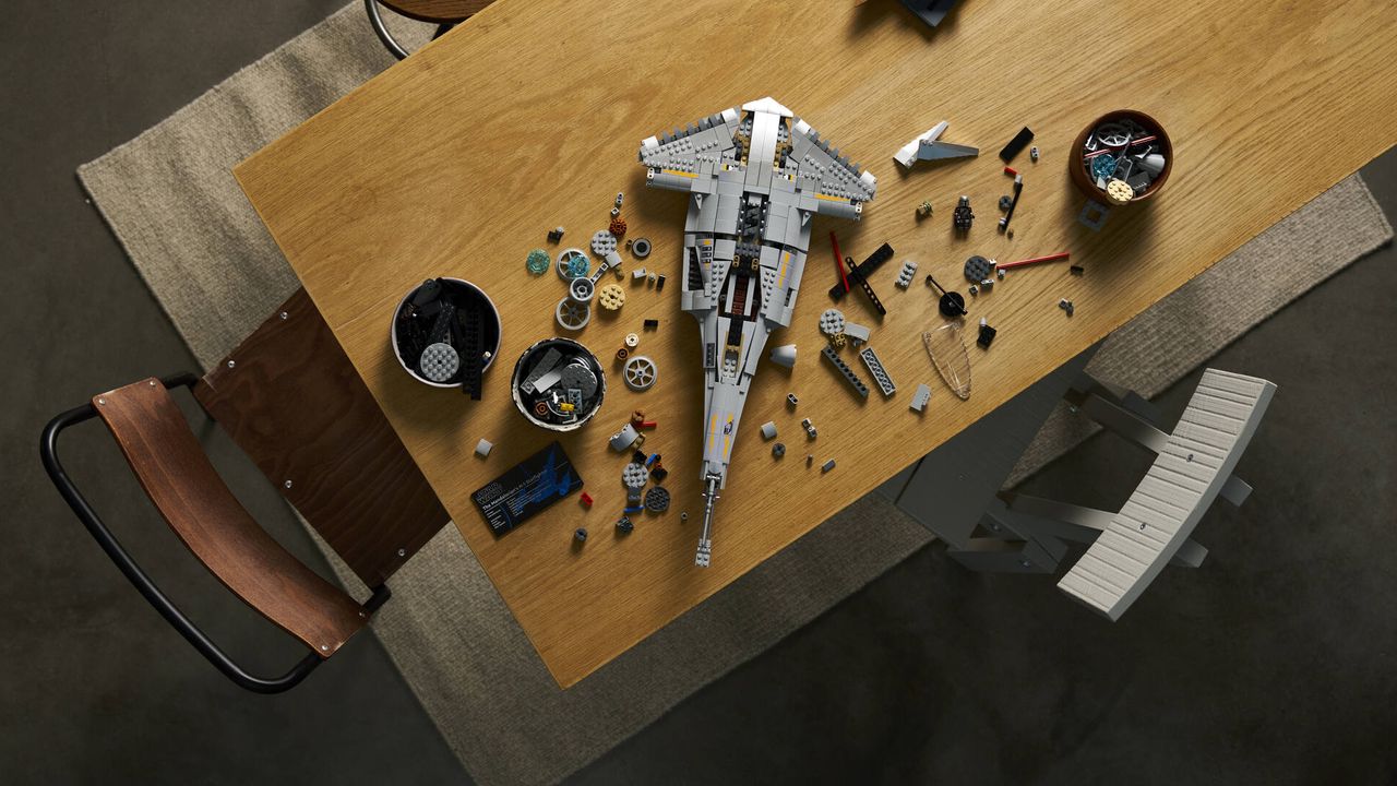 A partially-built Lego N1 Starfighter in pieces on a wooden table